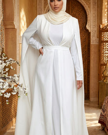  Cape longue blanche Elegance Zaina Maxi pour une tenue de mariage, portee sur une tenue blanche avec ceinture en tissu.