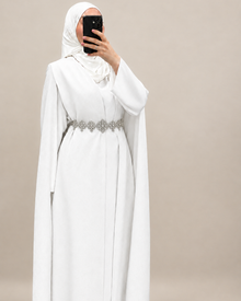 Cape mariee longue blanche Elegance Zaina Maxi portee avec un hijab blanc et une ceinture argentee en accessoire