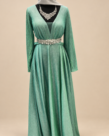 Robe longue verte scintillante sur fond beige