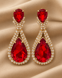 Détail des boucles d’oreilles rouges sur tissu beige