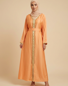 Robe longue abricot à strass dorés et ceinture portée par une mannequin sur fond beige