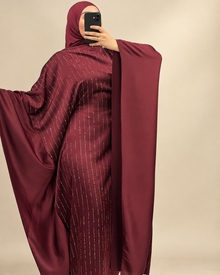 Abaya bordeaux, manches cape déployées sur fond beige