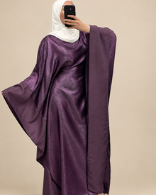 Robe prune avec manches cape déployées sur fond beige