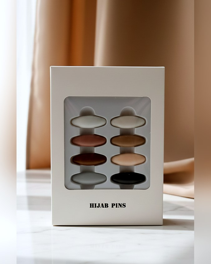 Boîte de huit épingles pour hijab aux coloris neutres, vue de face.