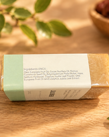 Savon au SIDR (jujubier) posé sur le côté, avec la liste des ingrédients visible sur son emballage blanc et vert.
