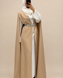 Cape longue beige Elegance Zaina Maxi portee sur une robe blanche avec une ceinture argentee, vue de face